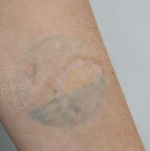 extremely faded colorful sun overlooking water tattoo