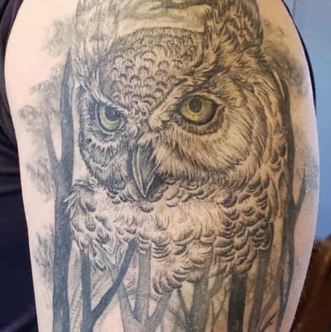 Tattoo of a detailed owl overlooking a forest