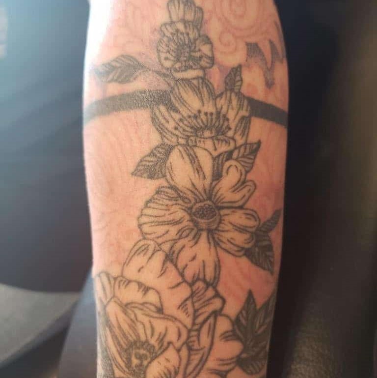 Tattoo of detailed flowers with a pattern behind them