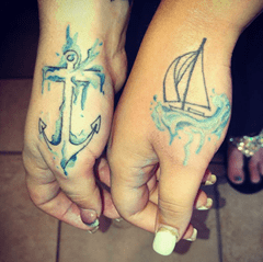 Tattoos of an anchor and a sailboat surrounded by water