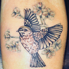 Tattoo of a bird surrounded by flowers