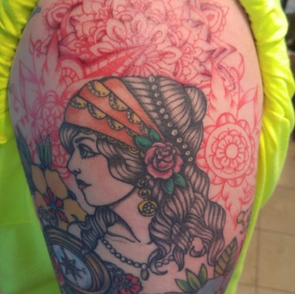 Tattoo of a detailed girl with a mosiac pattern of flowers behind her