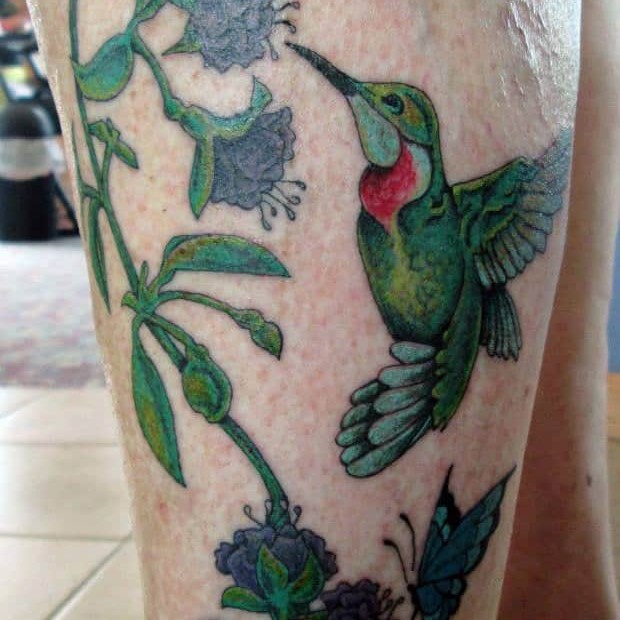 Tattoo of a hummingbird by a flower