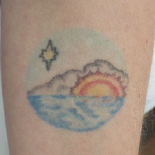 colorful sun overlooking water tattoo