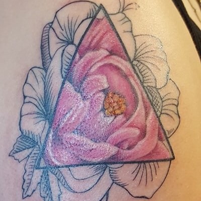 Tattoo of a black and white flower on the outside of a triangle, with the inside of the triangle having the flower in color